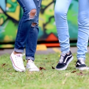 Two people's legs in jeans wearing sneakers