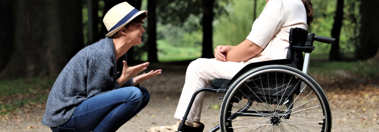 one young person in a wheelchair having a chat to another young person outdoors