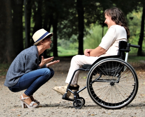 one young person in a wheelchair having a chat to another young person outdoors