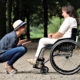 one young person in a wheelchair having a chat to another young person outdoors
