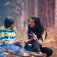 Two women sitting in front of a campfire and talking with each other