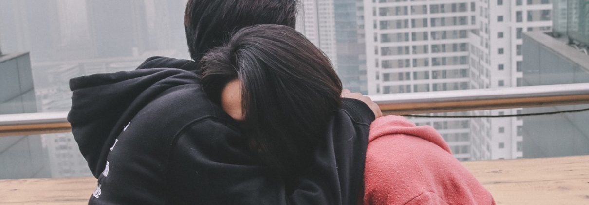 young woman being hugged by young man