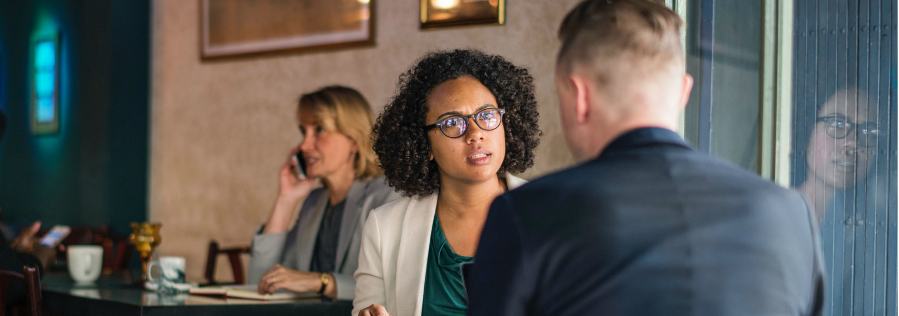 Woman with angry look facing man with back to camera while sitting in cafe