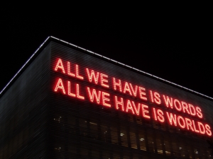 neon lights that say "all we have is words, all we have is worlds"