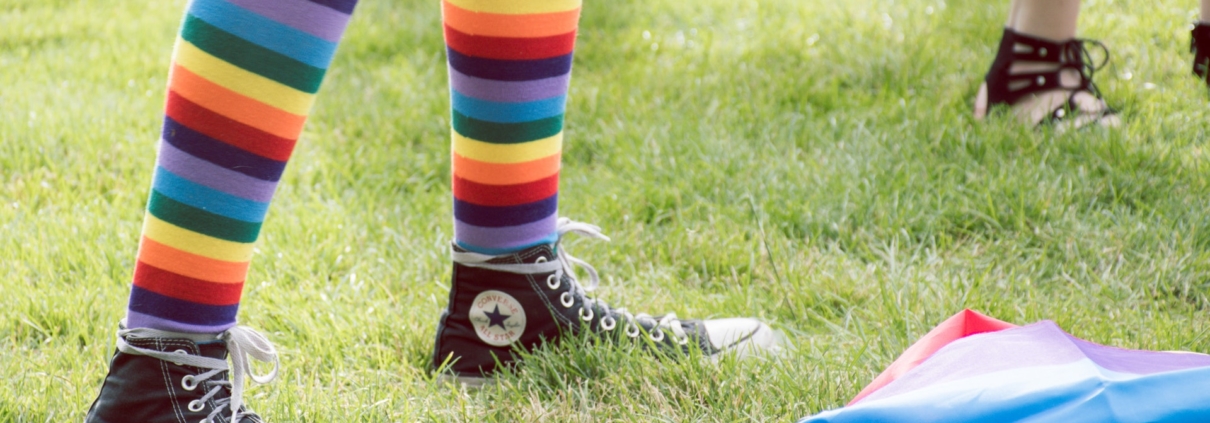 legs wearing rainbow socks and black Converse sneakers