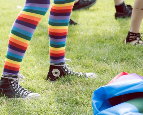 legs wearing rainbow socks and black Converse sneakers