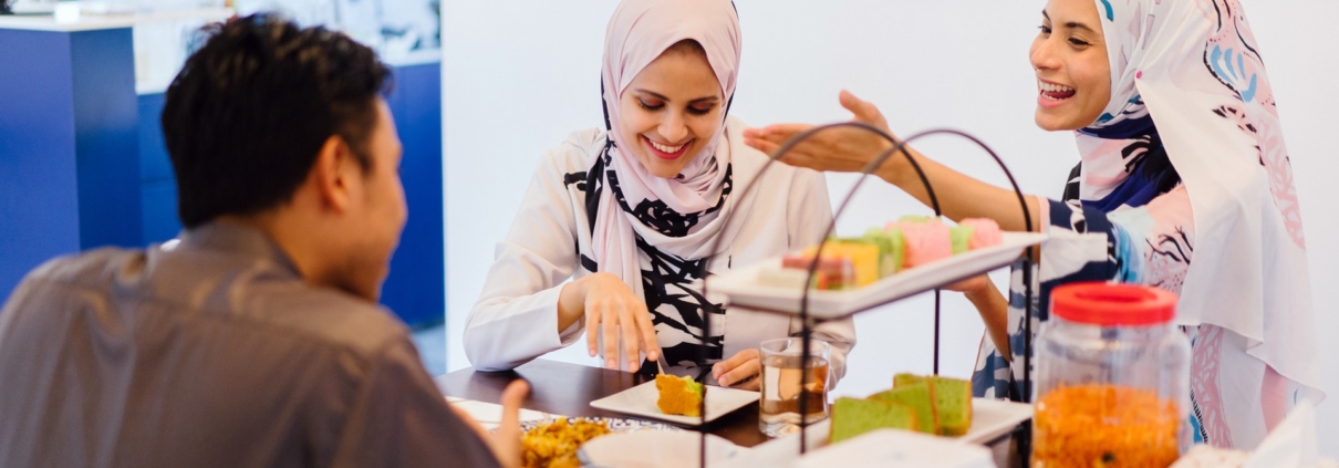 Two women and a man talking and smiling while eating cake