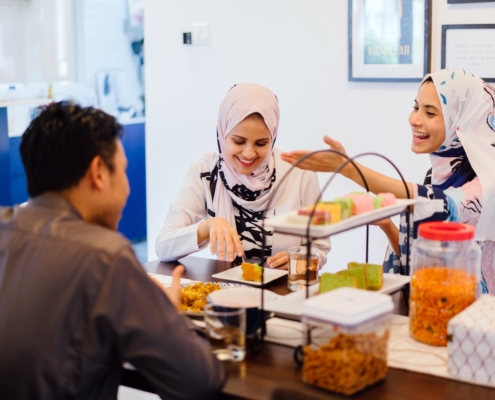 Two women and a man talking and smiling while eating cake