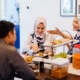 Two women and a man talking and smiling while eating cake