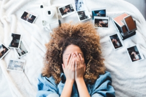 woman covering her face and surrounded by polaroids