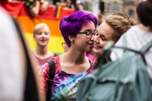 woman wearing tie die shirt kissing another woman