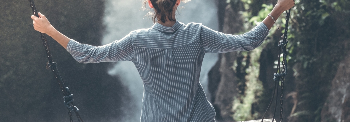 Woman sitting on a swing over a valley in the mountains