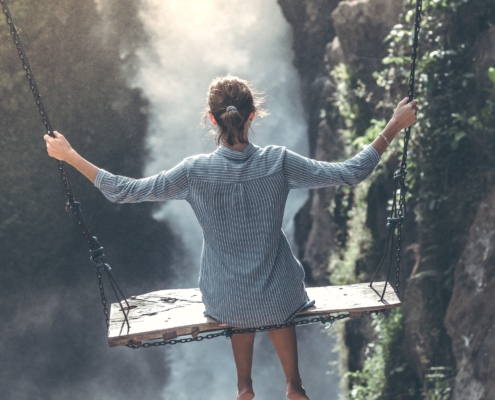 Woman sitting on a swing over a valley in the mountains