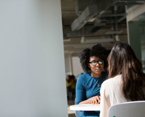 Two women sitting across from each other at a table in conversation