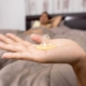 Condom sitting on top of a hand with background image showing a man under a bed sheet