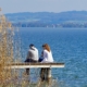 Man and woman sitting on a jetty over a lake and talking