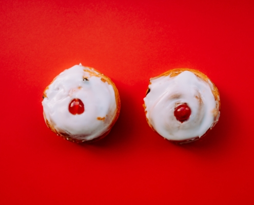 two white frosted cupcakes with cherry toppings