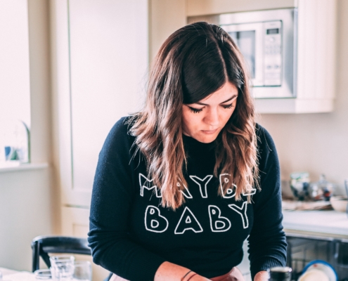 young woman wearing 'maybe baby' top